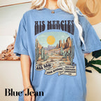 a woman wearing a blue tshirt with a desert scene on it