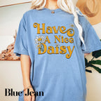 a blonde woman wearing a blue t - shirt that says have a nice daisy