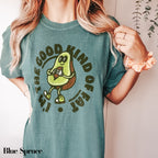 a woman wearing a green t - shirt with an avocado on it
