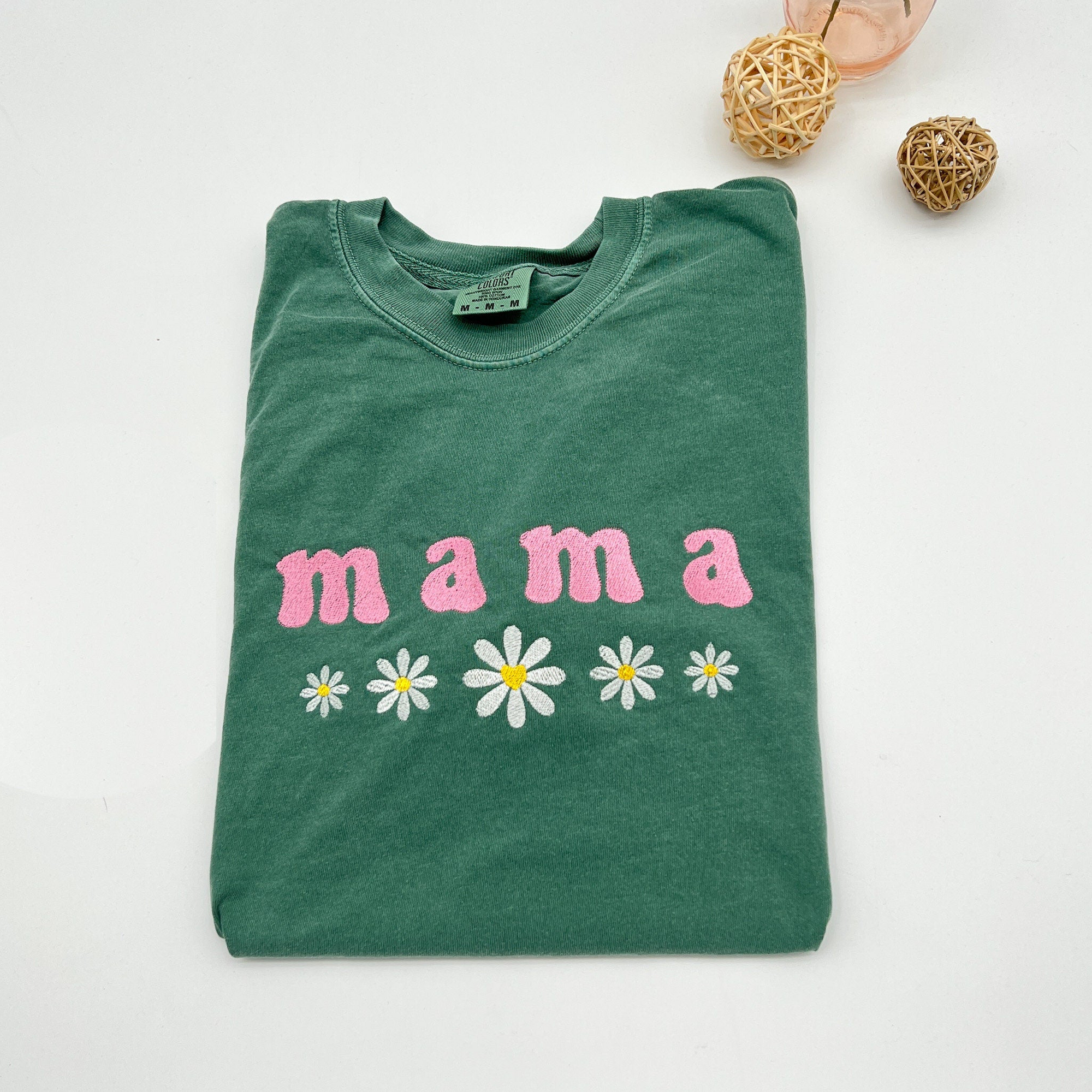 a green t - shirt that says mama with daisies on it